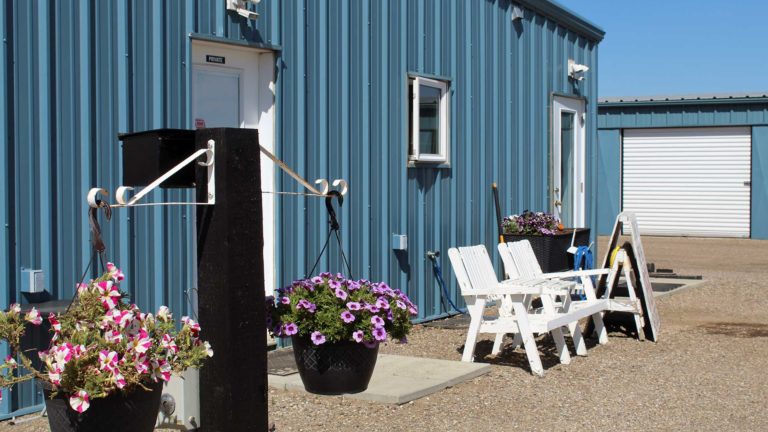 Photo of Calgary and Airdrie self storage site office front door with bench and flowers