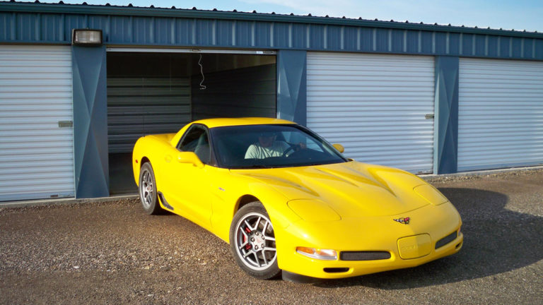 Photo of yellow Corvette backing up into a self storage unit